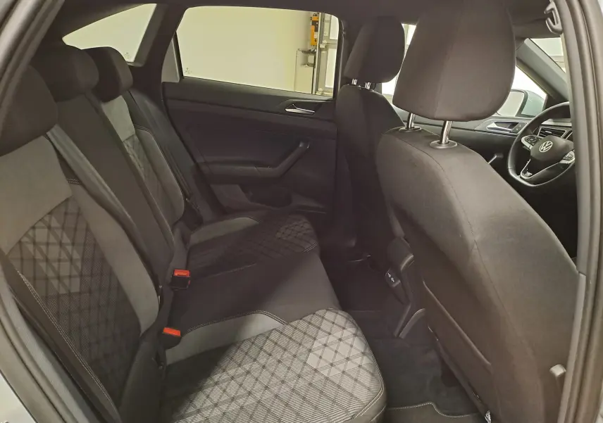 Vue intérieure arrière droite du Volkswagen Taigo 1.0 TSI R-Line 2024, sièges tissu à motifs et tableau de bord noir.