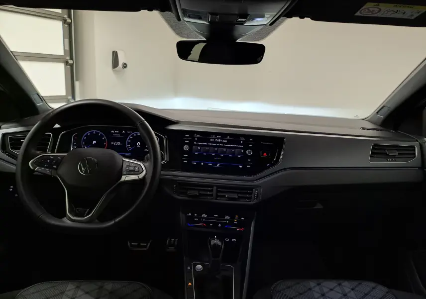 Intérieur du Volkswagen Taigo 2024 R-Line, vue du poste de conduite avec tableau de bord numérique et écran central tactile.