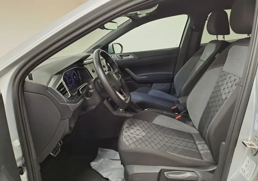 Intérieur du Volkswagen Taigo 1.0 TSI R-Line 2024, vue côté conducteur, sièges noirs avec surpiqûres et volant multifonction.