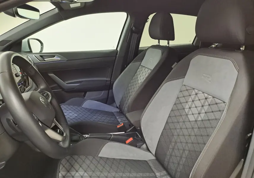 Vue intérieure côté conducteur du Volkswagen Taigo 1.0 TSI R-Line 2024 avec sièges en tissu gris à motifs géométriques.
