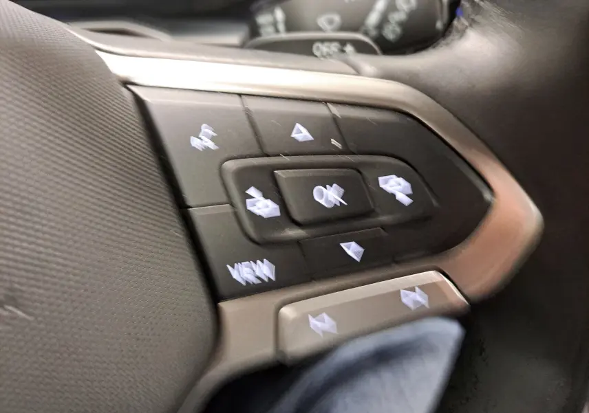 Gros plan sur les commandes au volant du Volkswagen Taigo 2024, version R-Line, avec boutons multifonctions et finition argentée.