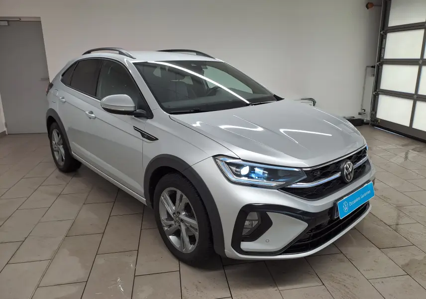 Volkswagen Taigo 1.0 TSI 110 DSG7 R-Line argent métallisé en 3/4 avant droit avec feux allumés en intérieur.