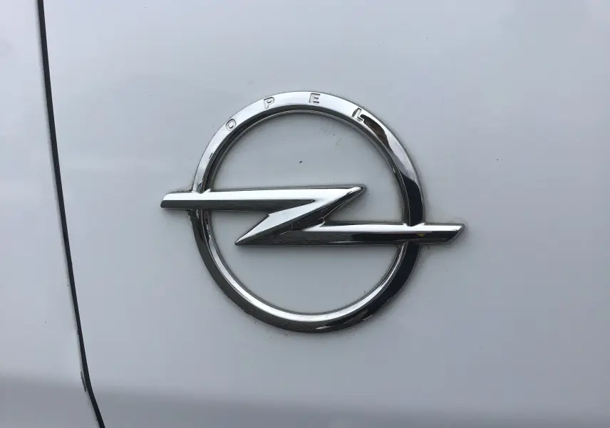 Gros plan sur l'emblème chromé Opel sur la carrosserie blanche du fourgon Vivaro M 1.5 BlueHDi 2022