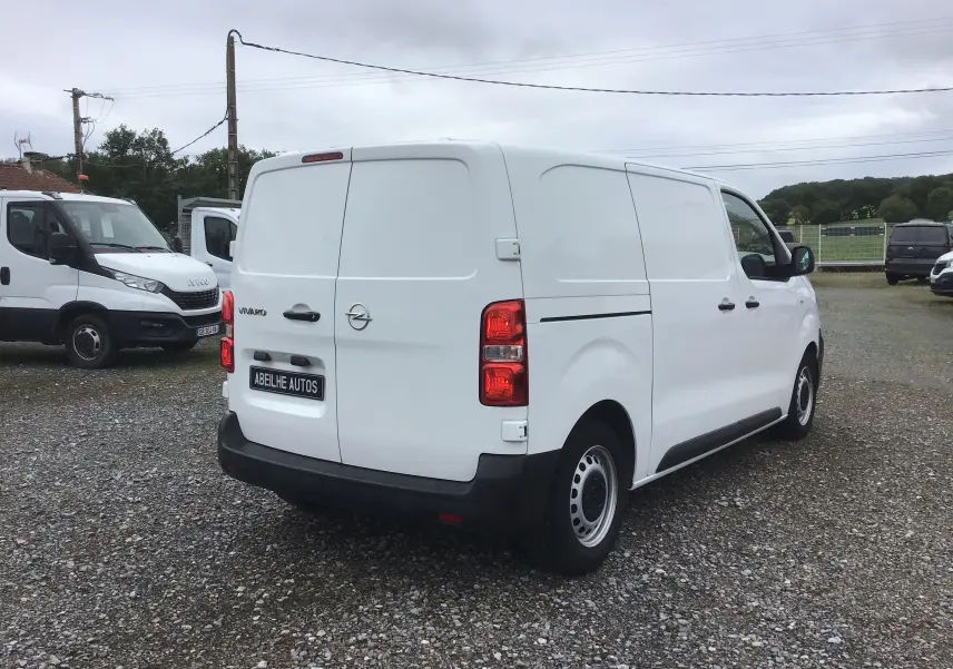 Vue 3/4 arrière droite d'un utilitaire Opel Vivaro blanc de 2022 avec portes arrière battantes et jantes acier noires.