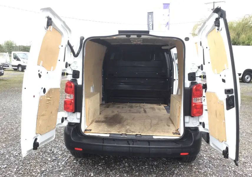 Vue arrière d'un Opel Vivaro blanc 2022 avec portes ouvertes montrant l'espace de chargement en bois.