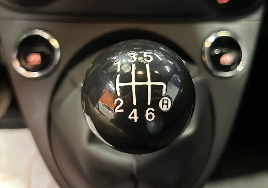 Gros plan sur le pommeau de la boîte manuelle noire à 6 vitesses de la FIAT 500 2023, version Pack Confort.