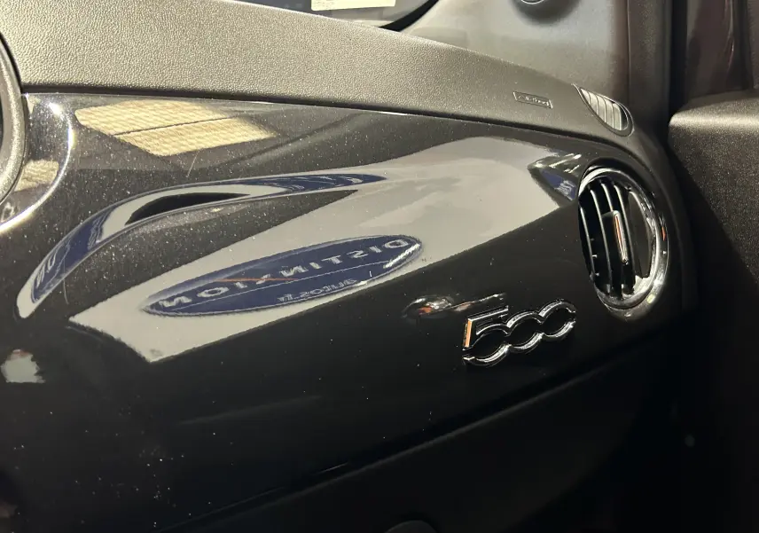 Tableau de bord noir brillant de la Fiat 500 2023 avec logo 500 et sortie d'air ronde côté passager.