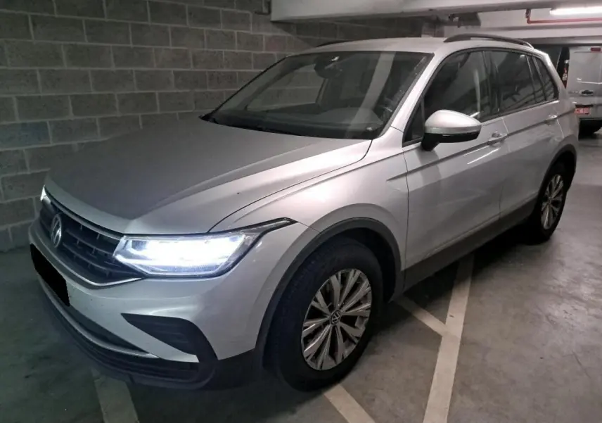 Volkswagen Tiguan 2.0 TDI 150 DSG7 Life argent fleuret en 3/4 avant droit avec feux LED allumés dans un parking.