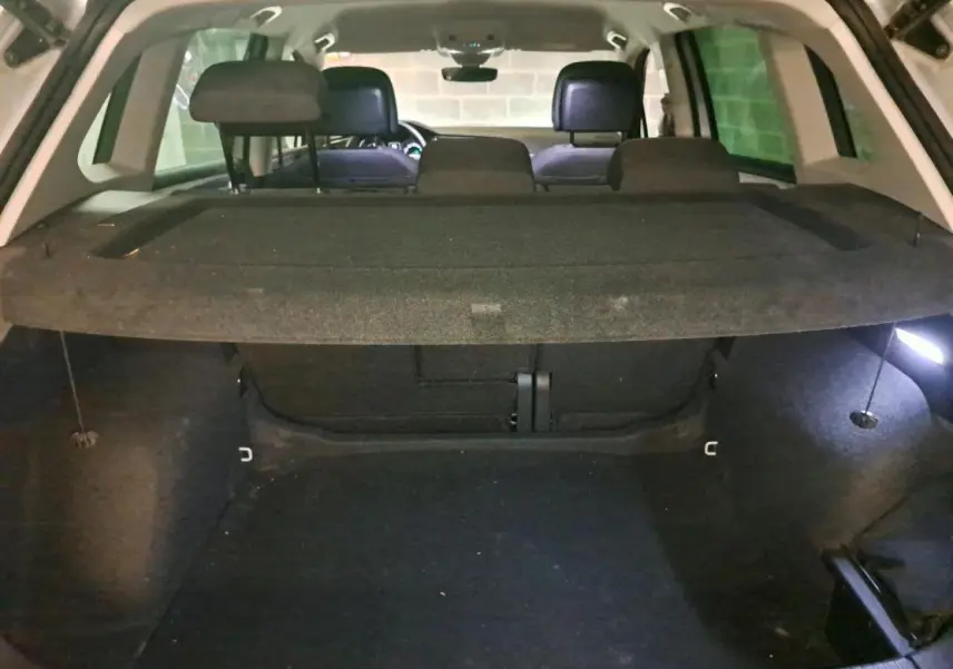 Vue intérieure du coffre ouvert du Volkswagen Tiguan 2.0 TDI 150 DSG7 Life argent, montrant l'espace de chargement et la plage arrière.