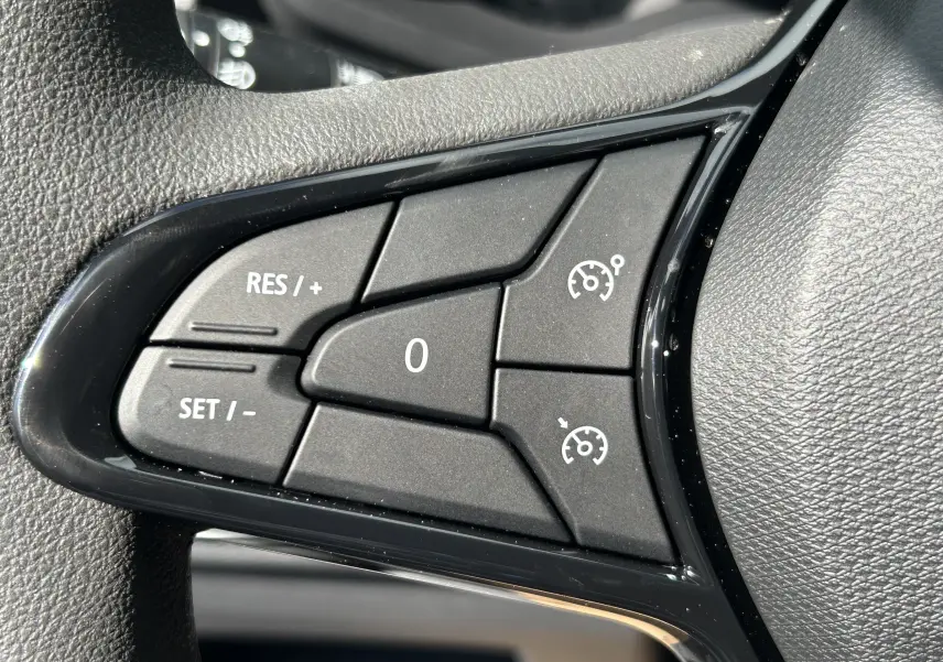 Gros plan sur les commandes de régulateur de vitesse au volant du Renault Trafic Combi blanc Glacier 2025.