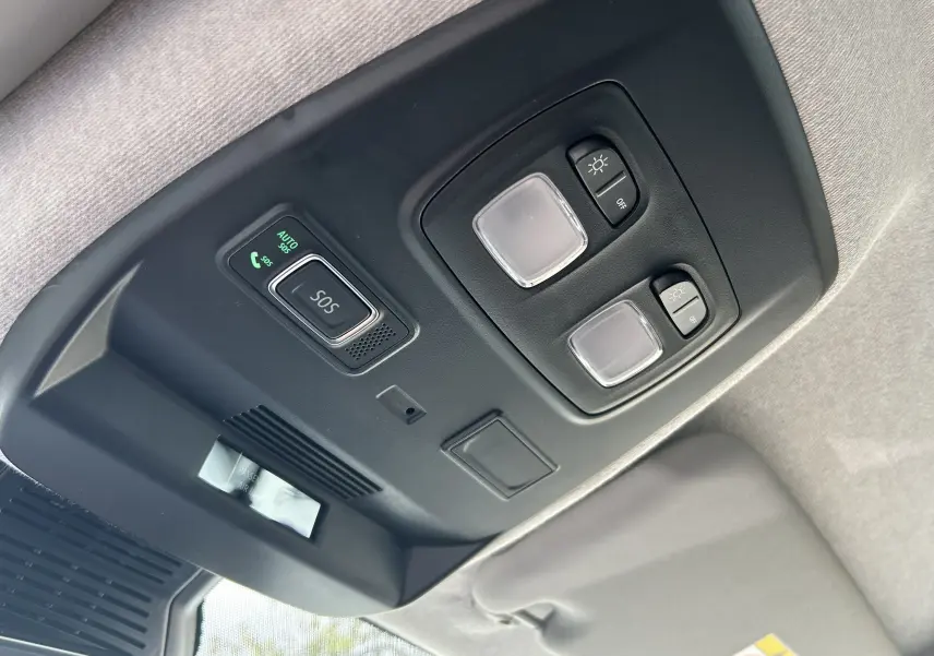 Plafonnier intérieur avec boutons d'éclairage et alerte SOS du Renault Trafic Combi blanc, vue en contre-plongée.