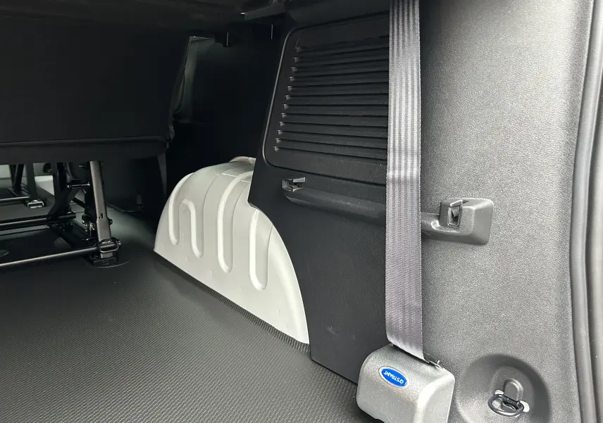 Détail intérieur côté gauche du Renault Trafic Combi blanc, montrant l'arceau de roue et la ceinture de sécurité.