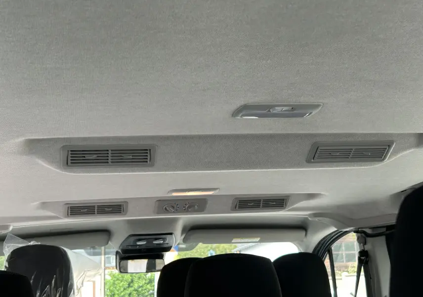 Vue intérieure du plafond et des aérateurs arrière du Renault Trafic Combi blanc Glacier, avec commandes de climatisation manuelle.
