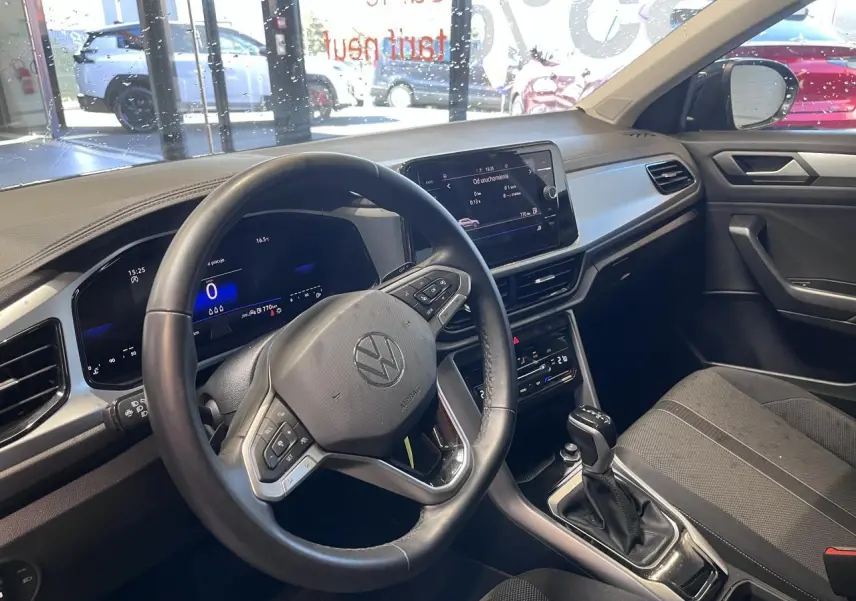 Intérieur du Volkswagen T-Roc 2025 vu côté conducteur, tableau de bord noir avec écran tactile et volant multifonction.