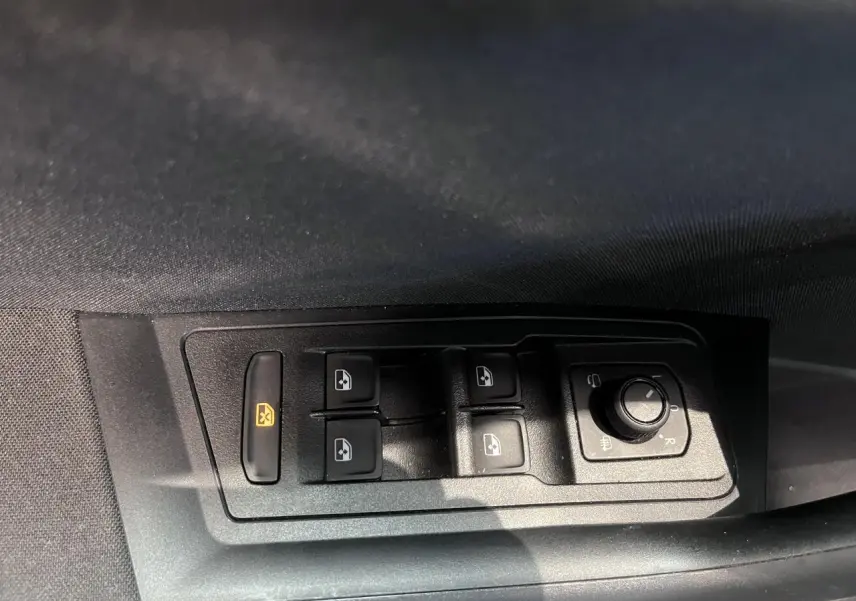 Gros plan sur les commandes de lève-vitres et réglage des rétroviseurs côté conducteur d’un Volkswagen T-Roc noir.