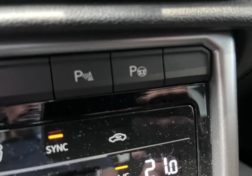 Gros plan sur la console centrale du Volkswagen T-Roc 2025, affichant la climatisation à 21°C en mode sync.