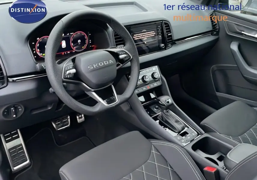 Vue intérieure du poste de conduite du Skoda Karoq gris argent 2025, avec volant multifonction et sellerie tissu noire matelassée.