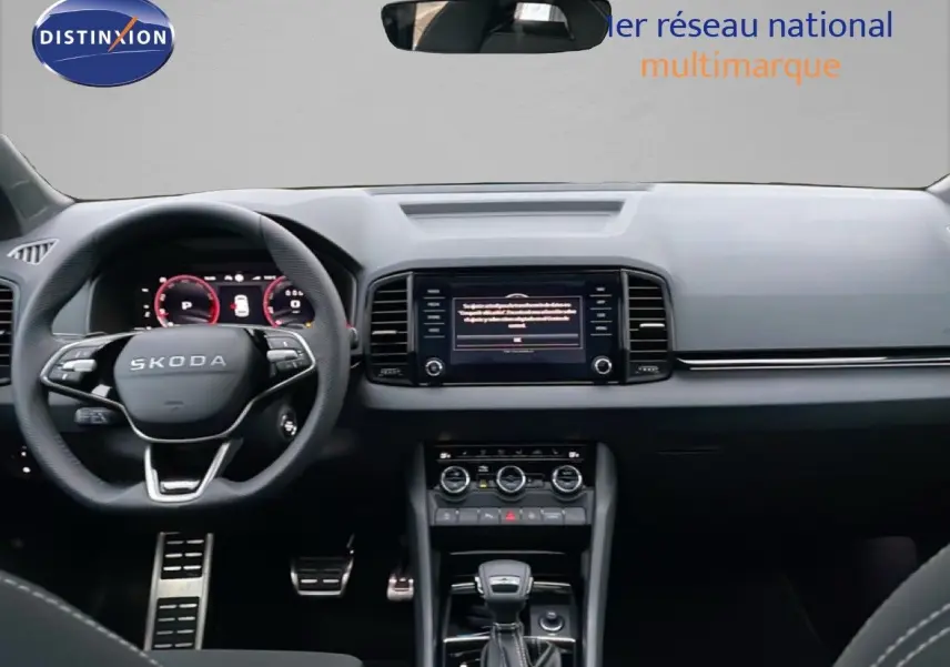 Vue intérieure avant du Skoda Karoq 1.5 TSI 2025, tableau de bord noir avec écran central tactile et volant multifonction.