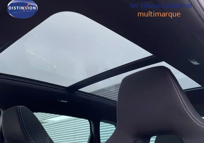 Toit panoramique ouvert vu de l'intérieur sur un Skoda Karoq gris argent 2025, sièges avant en cuir noir.