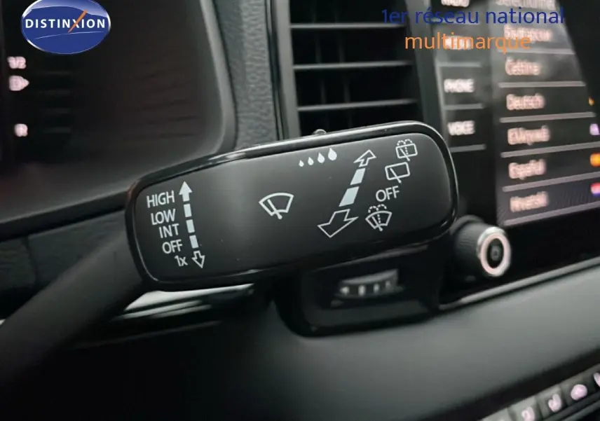 Gros plan sur la commande des essuie-glaces du Skoda Karoq gris argent, avec tableau de bord et écran tactile en arrière-plan.