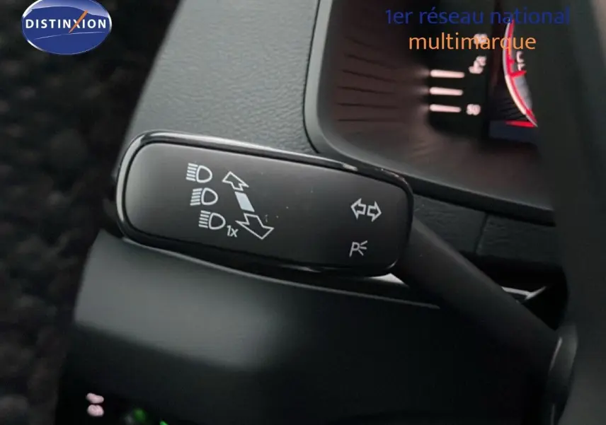 Gros plan sur la manette de clignotant et feux du Skoda Karoq 1.5 TSI gris argent, intérieur noir visible en arrière-plan.