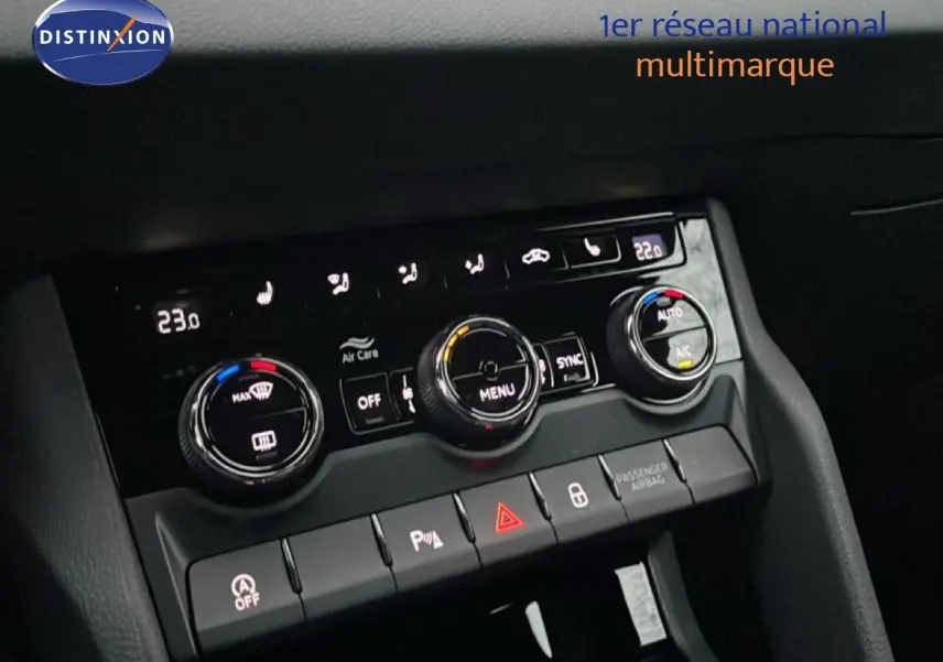 Gros plan sur la console centrale du Skoda Karoq gris argent, montrant les commandes de climatisation et les boutons de sécurité.