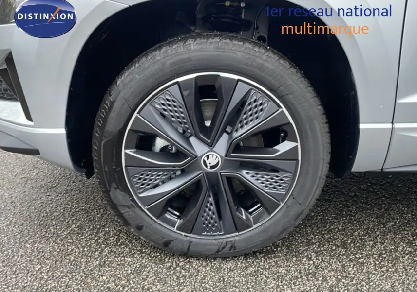 Gros plan sur la roue avant droite d’un Skoda Karoq gris argent métal, mettant en valeur la jante noire au design moderne.