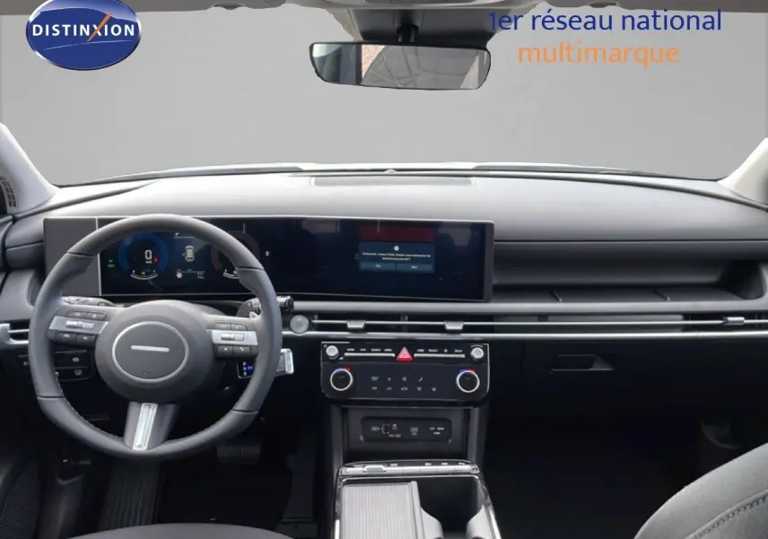 Vue intérieure avant du Hyundai Tucson 2026, tableau de bord noir avec écran large et volant multifonction.