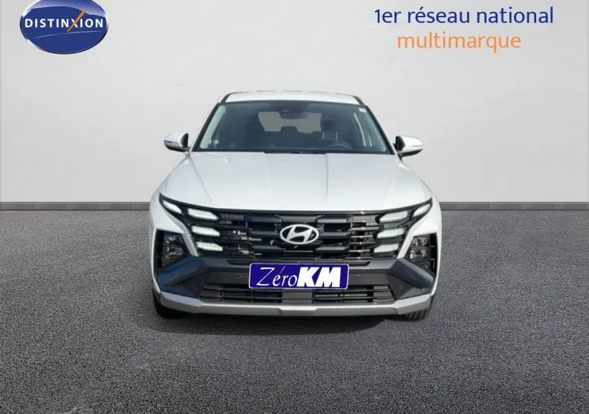 Vue frontale d'un Hyundai Tucson blanc Atlas 2026 avec calandre noire distinctive et feux LED intégrés.