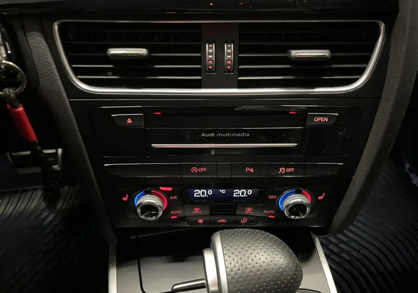 Vue rapprochée du tableau de bord central noir de l'Audi A5 Sportback avec commandes climatisation et levier de boîte auto.