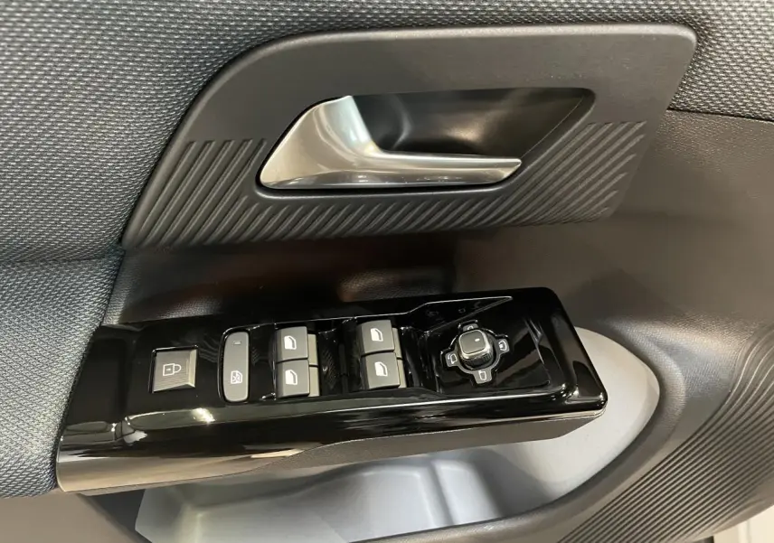 Gros plan sur la commande de lève-vitres et rétroviseurs côté conducteur du Citroën C5 Aircross 2026 avec garniture noire texturée.