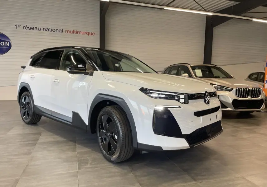Vue 3/4 avant d'un Citroën C5 Aircross blanc Okenite avec toit noir et jantes alliage noires en showroom.