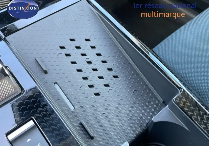 Détail du chargeur sans fil et console centrale noire du Citroën C5 Aircross Hybrid 2026, intérieur tissu bleu.