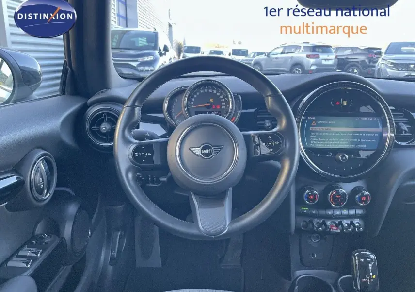 Vue intérieure du tableau de bord et volant noir de la MINI Cabriolet F57 2023 avec écran central rond et commandes lumineuses.