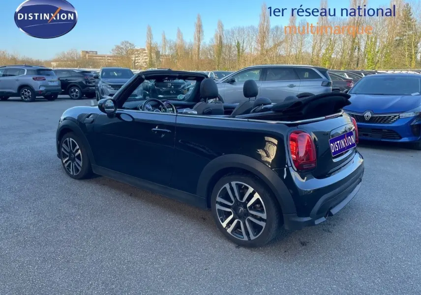 MINI Cabriolet noir Midnight Metal vue 3/4 arrière droit avec capote ouverte sur parking extérieur.