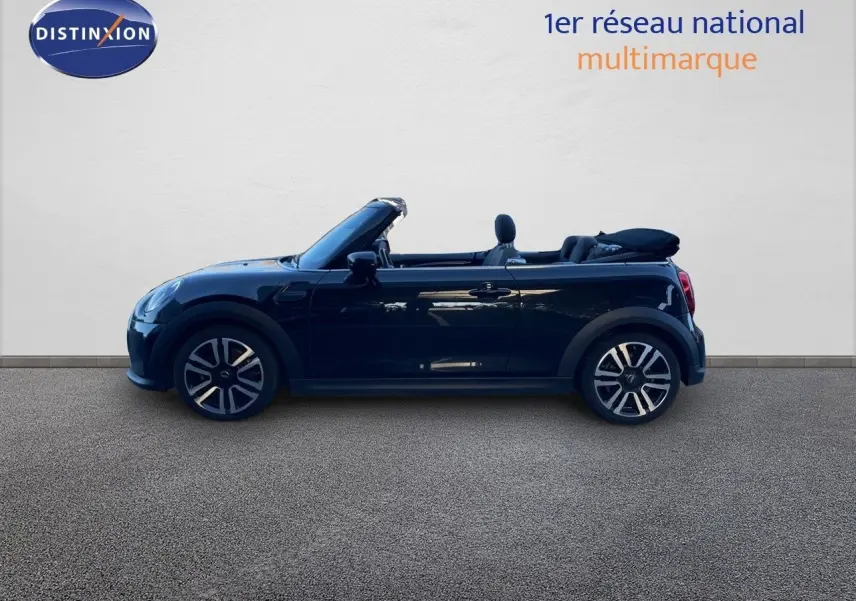 Profil côté gauche d'une MINI Cabriolet 2023 noir midnight metal avec capote repliée et jantes bi-ton.