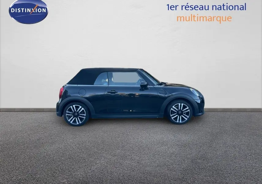 Profil côté gauche d'une MINI Cabriolet F57 noire avec capote fermée, soulignant ses jantes bi-ton et lignes compactes.