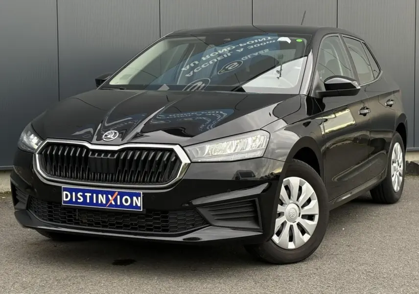 Vue 3/4 avant d'une Skoda Fabia 2024 noir Magic garée sur un sol pavé devant un bâtiment blanc.