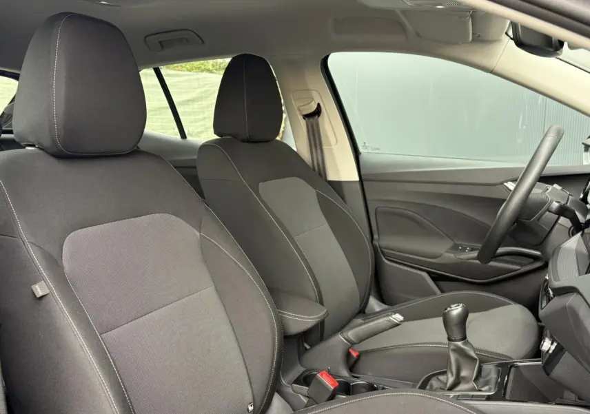 Vue intérieure côté conducteur de la Skoda Fabia 2024 noire, volant cuir, écran tactile et levier de vitesses manuel visibles.