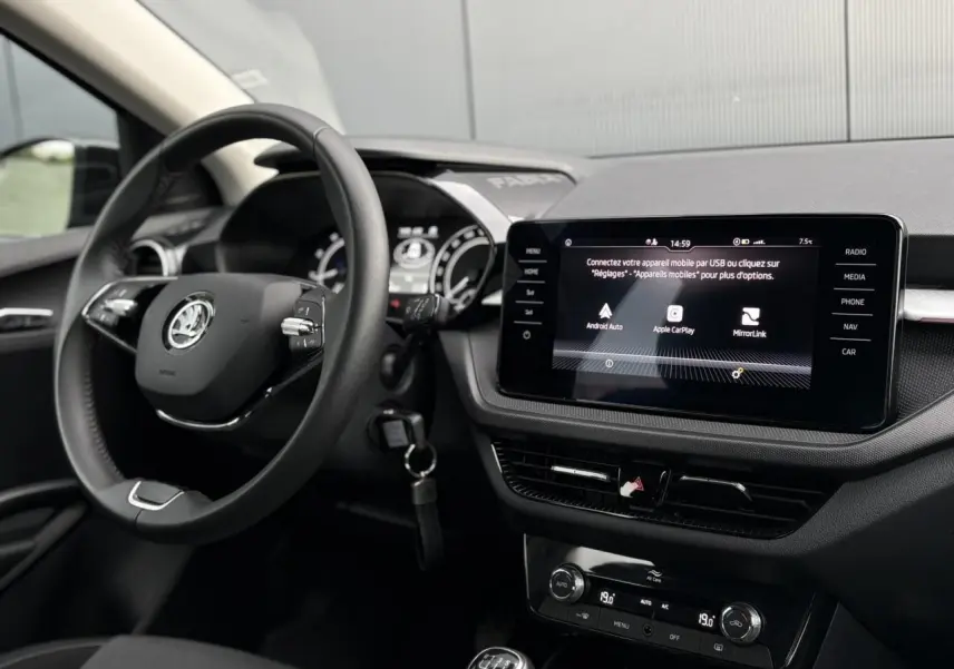 Vue intérieure côté conducteur de la Skoda Fabia 2024 noire Magic, siège tissu avec réglage lombaire manuel visible.