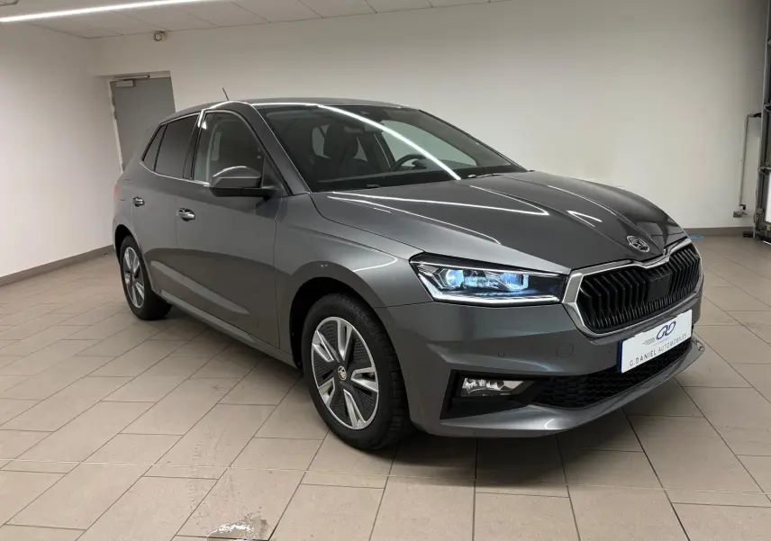 Skoda Fabia 2023 gris graphite métallisé vue 3/4 avant droit avec phares LED allumés en intérieur.