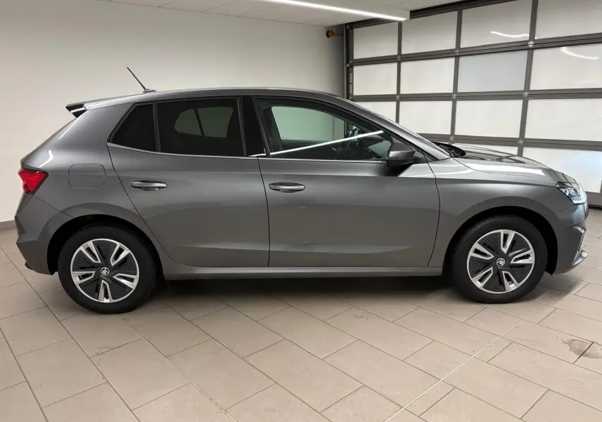 Vue de profil côté gauche d'une Skoda Fabia 2023 gris graphite métallisé avec jantes spécifiques et antenne sur le toit.