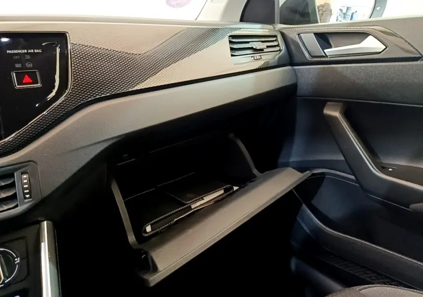 Intérieur côté passager du Volkswagen Taigo noir 2023, boîte à gants ouverte avec carnet à l'intérieur.