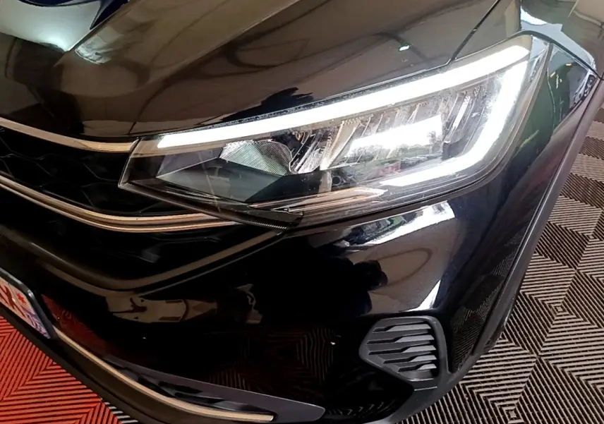 Gros plan sur le phare avant droit allumé d'un Volkswagen Taigo noir 2023, mettant en valeur la calandre et les détails LED.