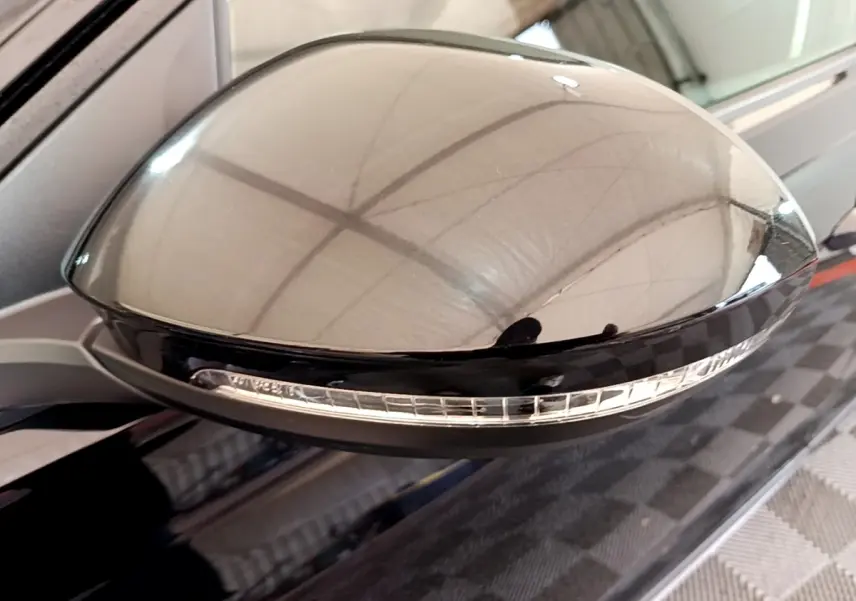 Gros plan sur le rétroviseur noir avec clignotant intégré du Volkswagen Taigo 1.0 TSI 95 Life côté conducteur.