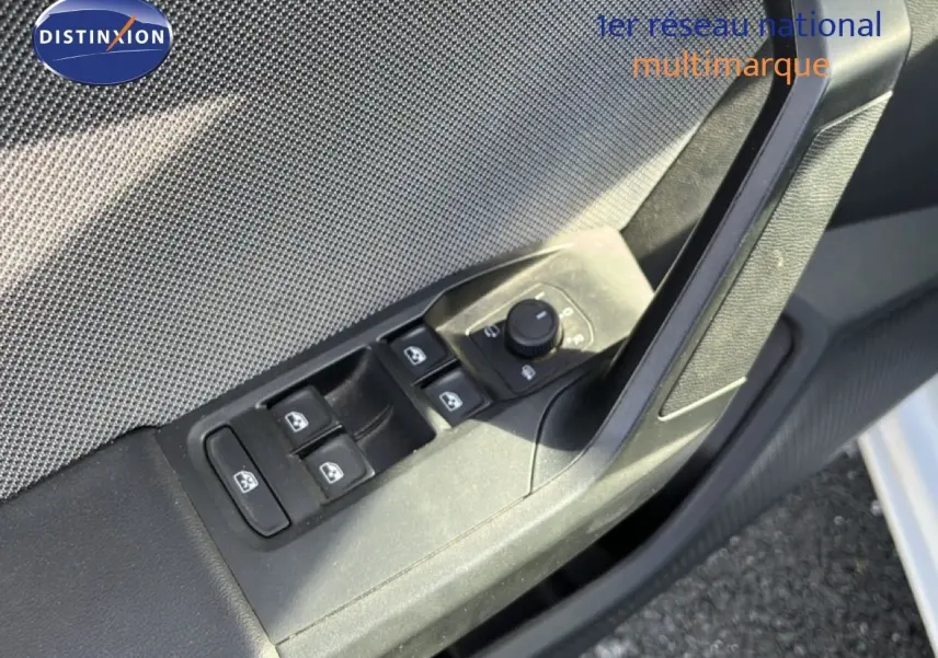 Gros plan sur la commande des vitres électriques côté conducteur d'une SEAT LEON blanc neige, intérieur tissu gris.