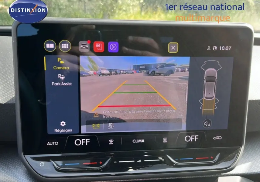 Écran tactile intérieur montrant la caméra de recul active d'une SEAT LEON blanc neige, version 2025, avec assistance au stationnement.