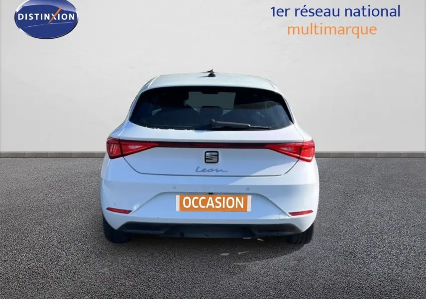 Vue arrière d'une SEAT Leon blanche neige 2025 avec feux LED et logo distinctif sur fond neutre.