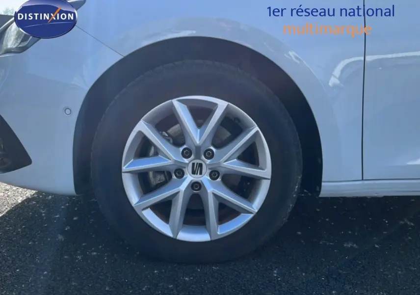 Gros plan sur la roue avant gauche d'une SEAT Leon blanc neige, mettant en valeur la jante en alliage argentée.