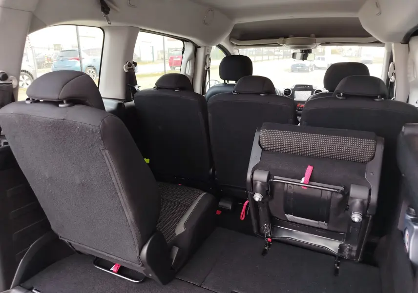 Vue intérieure arrière du Peugeot Partner Tepee gris foncé, montrant les sièges arrière dont un partiellement replié.